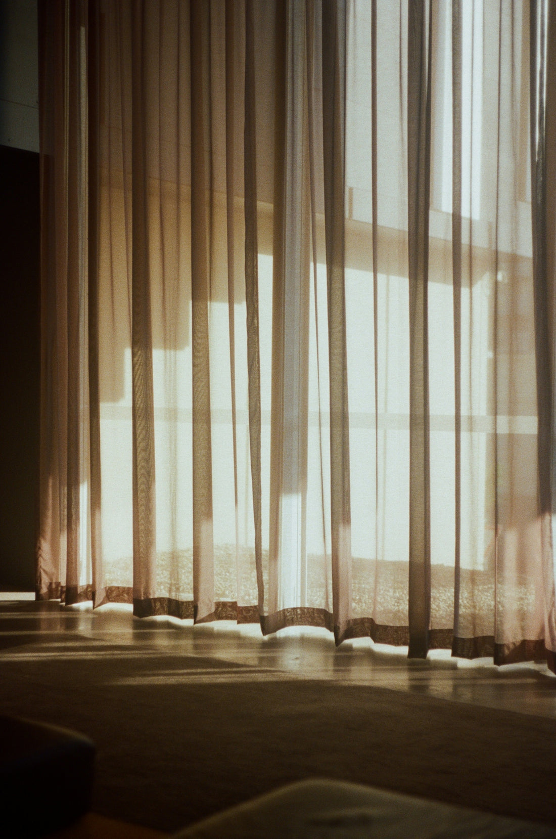 a room with a bed and a window with sheer curtains